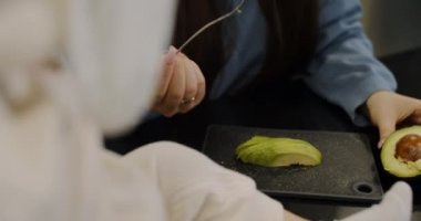 Genç anne, küçük çocuğu parçada avokado ile besler. Yavaş çekim.