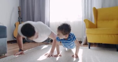 Gün batımında babasıyla birlikte oturma odasında spor yapan komik bir çocuk..