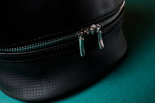 A black leather bag, on a garden background in a minimalist style, flower decor.