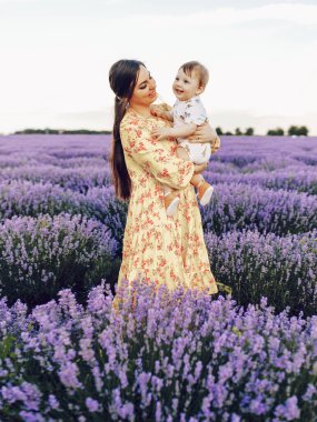 Genç anne küçük oğluyla lavanta tarlasında oynuyor, kollarında..