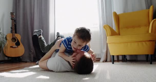 Padre juega con el niño, hijo pequeño, en casa en la sala de estar. Niño feliz.. — Vídeos de Stock