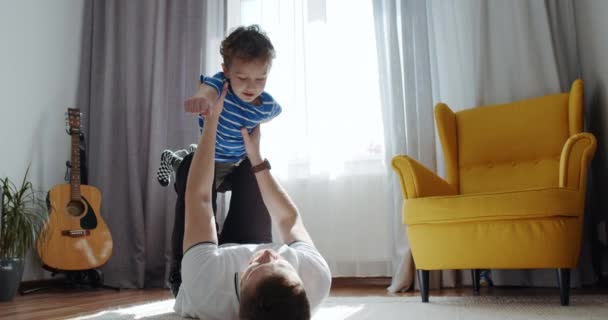 Fadern leker med barnet, den unge sonen, hemma i vardagsrummet. Lyckligt barn. — Stockvideo