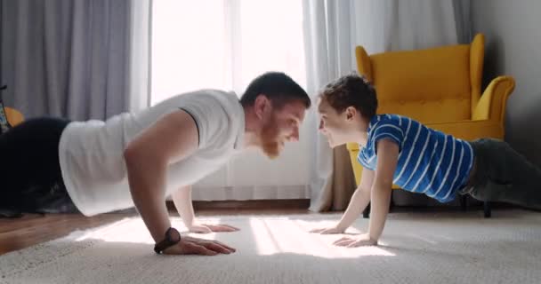 Sport zu Hause im Wohnzimmer Papa mit seinem kleinen süßen Sohn. — Stockvideo