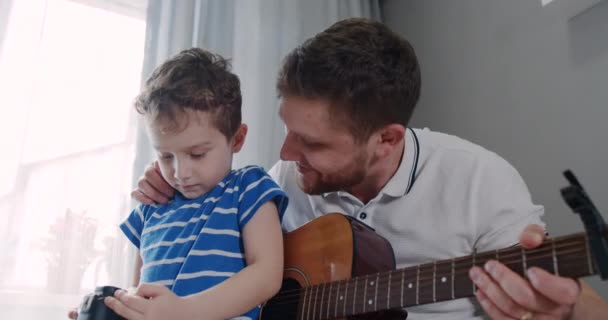 Little son, show his father what pictures he took of the camera. Dad with guitar — Stock Video
