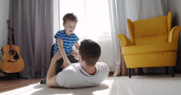 Padre juega con su hijo, niño, a casa en el suelo. Alegre y sonriente — Vídeo de stock