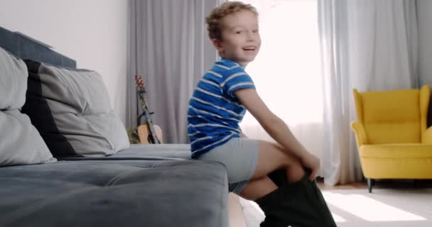 A little boy dresses in pants in the morning, prepares for the exit — Wideo stockowe