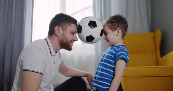 Jovem pai e seu filho com cabelo encaracolado jogando futebol. — Vídeo de Stock