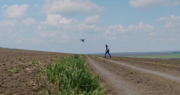 Un granjero camina en el campo y usa un dron moderno. tecnología. — Vídeos de Stock