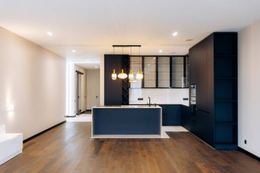 A stylish minimalist kitchen with sleek features, black accents, and warm wooden flooring, embodying modern aesthetics