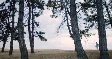 Two individuals enjoying a peaceful stroll together through a beautiful grassy area surrounded by tall pine trees