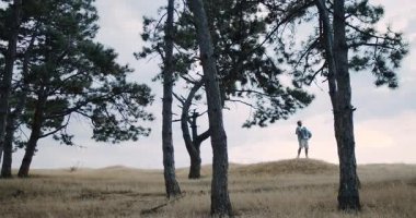 A picturesque scene of a couple among tall trees and grassy hills, showcasing love and tranquility in nature