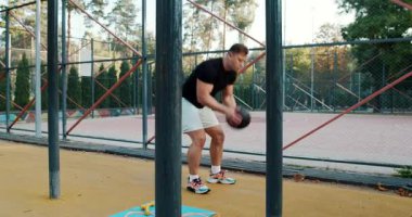 A fitness enthusiast performs dynamic exercises with a medicine ball in a beautiful outdoor setting