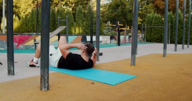 A man is actively performing abdominal exercises on a yoga mat while enjoying a park setting filled with nature