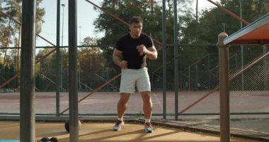 A dedicated and focused athlete is diligently performing various workout routines in an outdoor gym setting