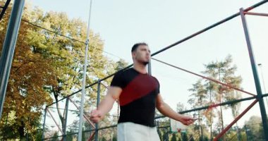 A man is actively engaged in jump rope training while being outdoors in a vibrant autumn park environment