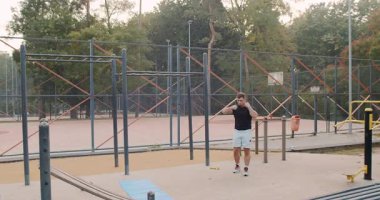 A man is engaging in exercises at an outdoor gym, effectively showcasing his strength training and cardio skills