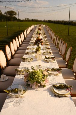 Mevsimsel aksanlarla süslenmiş günbatımının hafifçe aydınlattığı sıradan bir yemek masası.