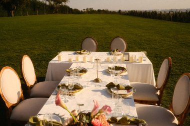 Mum ve dekorlu romantik bahçe sahnesi, yumuşak ışıklandırmalı ve çiçekli manzaralı masa düzenlemesi.