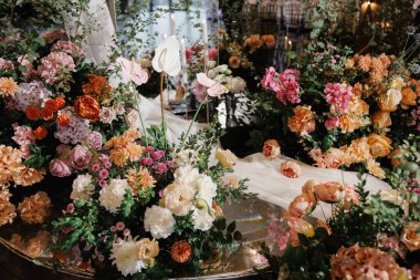 Romantik ışıklandırmayla gösterişli çiçek süsü mumların arasında süslü dekoratif detaylarla süslü bir düzenleme.