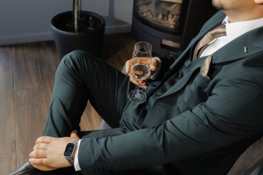 Bishop zarif giyinmiş, takım elbiseli, viski içen, sıcak şöminenin yanında kendine güvenen bir damat.