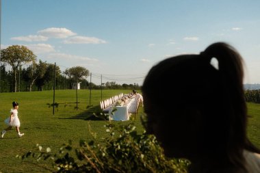 Çocuk gün batımında masaya yaklaşır, Serene aile etkinliği altın saatinde, çocuk şenlik masasına doğru giderken.