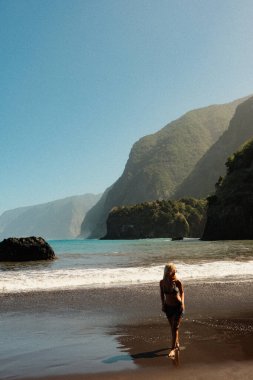 Sahil şeridindeki yalnız gezgin, Alacakaranlık 'taki abanoz kumlu sahil şeridi boyunca sakin anların tadını çıkarıyor.