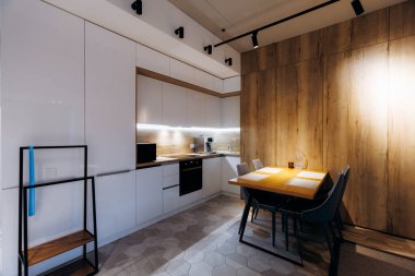 Modern mutfak köşesinde yemek masası, gösterişli dolaplar ve entegre aletler, parlak kabin altı aydınlatma ve temiz