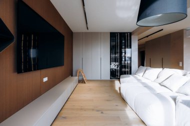 Duvara monte edilmiş az sayıda televizyon, düşük profilli kanepe, sıcak ahşap paneller, ortamın tenha aydınlatması ve küratörlü...