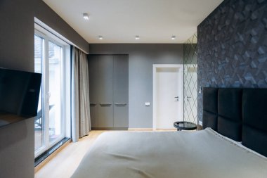 Parlak tek renkli yatak odası, gardırobu ve televizyonu var. Geniş döşemeli, kaygan yatak başlıklı modern çift için tasarlandı.