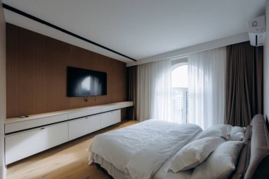 Taze beyaz yatak odası, perdeler, doğal meşe döşemesi ve yumuşak gün ışığı, ideal minimum atmosfer.