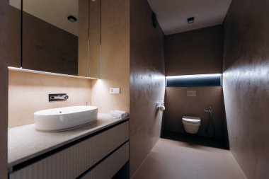 Led aksanlı, kasvetli bir banyo. Karanlık dar alan duvar dokularını, seramik armatürleri, gizli tuvaletleri, dramatik