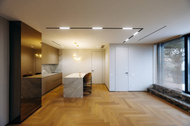 Meşe parke döşemeli, parlak dolaplı mermer mutfak, tenha aydınlatma ve sükunet yaratan kolye armatürleri