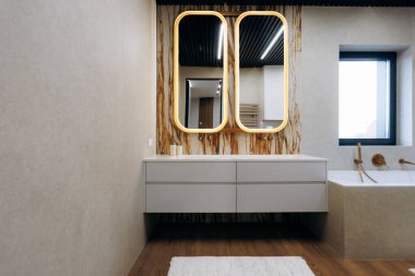 Çift aynalı mermer kibir ve beyaz tezgah, altın armatürler ve desenli halı sabah rutini için spa atmosferi yaratır.