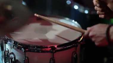 Trampet yakın çekim rimshot vuruşları, canlı saldırı ve yankılanan ton, kırmızı sahne arkası ışığı, sıkı cep hissi, davulcu