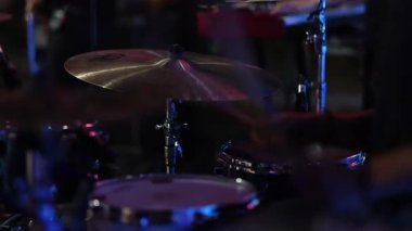 davul seti zille yakın çekim, sopalar çarpıcı tuzaklar ve tomlar, renkli sahne ışıkları, dinamik bina yoğunluğu,