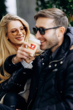 Arkadaşlar sıcak içeceklerin tadını çıkarırlar, bir çift serbest çalışan soğuk havanın tadını çıkarırlar, dışarıda kahve ve neşeli anların tadını çıkarırlar.