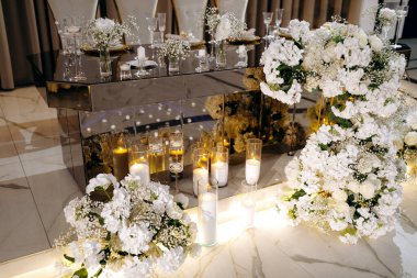 Çiçek açan dekorlu lüks yansıtıcı masa, aynadan yansıyan yüzey üzerinde mum ışığında çiçekler bulunan samimi ortam