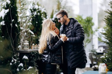 Parıltının altındaki aşıklar, rengarenk dekorasyonlar çevrelerinde şenlikli bir ortam oluştururken iki birey sevgi dolu kucaklaşmayı paylaşıyor.