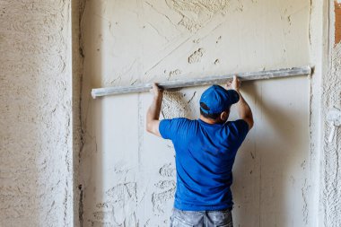 Tecrübeli müteahhit titizlikle tavana ve duvara yeni yapıştırılmış alçıyı kusursuz el hareketleriyle düzeltiyor.
