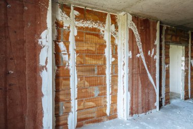 Açığa çıkmış tuğla ve yalıtım hatlarına sahip inşaat alanı, ham dokuların ve bina yapısının yer aldığı yenileme sahnesi