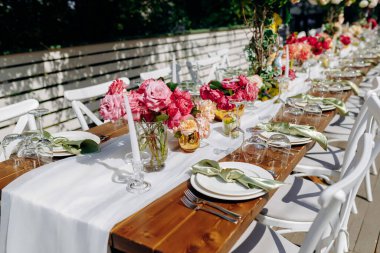 Yaz bahçesi kutlaması, parlak çiçekli masa düzenleme, ışıl ışıl yaz yemeği masasındaki neşeli çiçek süslemeleri.