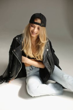 Kendine güvenen, kendine güvenen, etkileyici, şık bir kadın kot pantolon ve gülümseyen tavırlarla rahat bir moda sergiliyor.