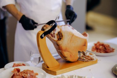 Yetenekli zanaatkar ince jambon dilimlerini incelikle dilimler, deneyimli aşçılar tarafından pişirilmiş jambonun zarif sunumu