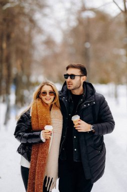 Sevgi dolu kış kucaklaşması, yumuşak gülümsemeleri ve rahat kıyafetleriyle karlı bir ortamda sevgi dolu bir bağ kuran çift.