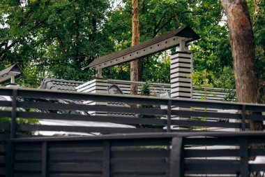 Gölgelendirme elementleriyle sakin arka bahçe sığınağı, ahşap yapılar ve yemyeşil yeşillikler içeren şehir dışı alan