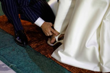 Düğün ayakkabısı ayarı, otantik sahne geline düğün sırasında ayakkabılarını giymesi için yardım eden damat görüntüsü.