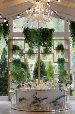 Zarif bir çiçek kutlaması, yeşil sallanan romantik bir masa, canlı çiçeklerle süslenmiş büyüleyici bir karşılama.