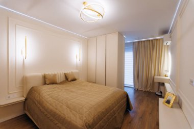 Yumuşak ortam avizesi, yumuşak yatak örtüsü, altın renkleri, süslü süsü, romantik bir gece manzarası için tasarlanmış rahat bir yatak odası.