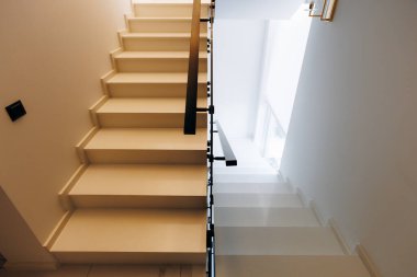 Parlak tavan penceresine giden siyah tırabzanlı minimalist beyaz merdiven, geometrik çizgiler ve derin gölgeler, temiz sonlar, ahşap.