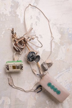 Old rusty wires and cables with distribution box (enclosure) and working lamp, symbol of electricity, renovation, repair or maintenance